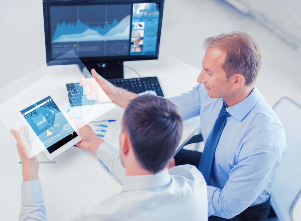  Men study trading charts on monitors.